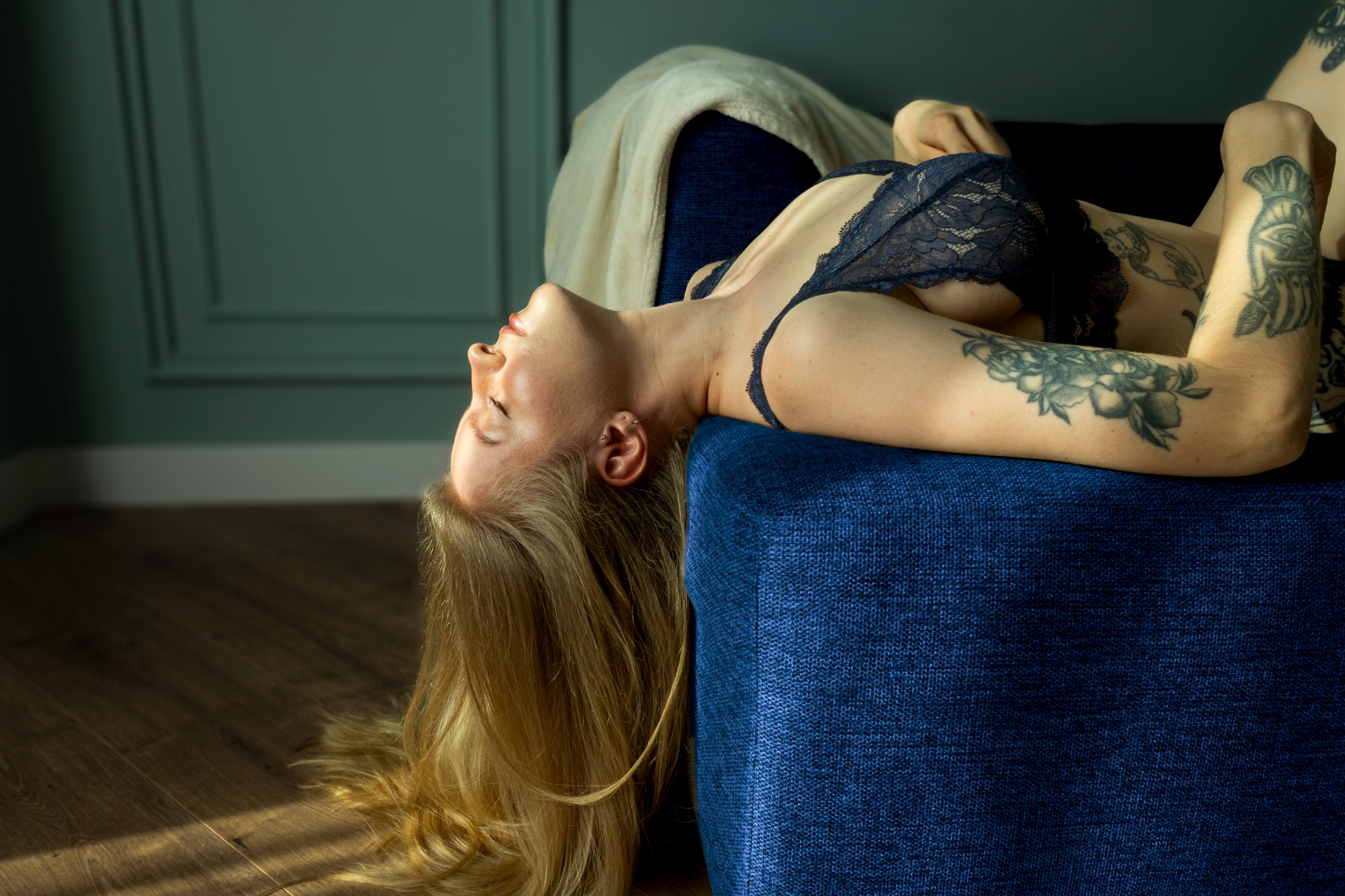 Vero reclining on a blue sofa in soft directional light.