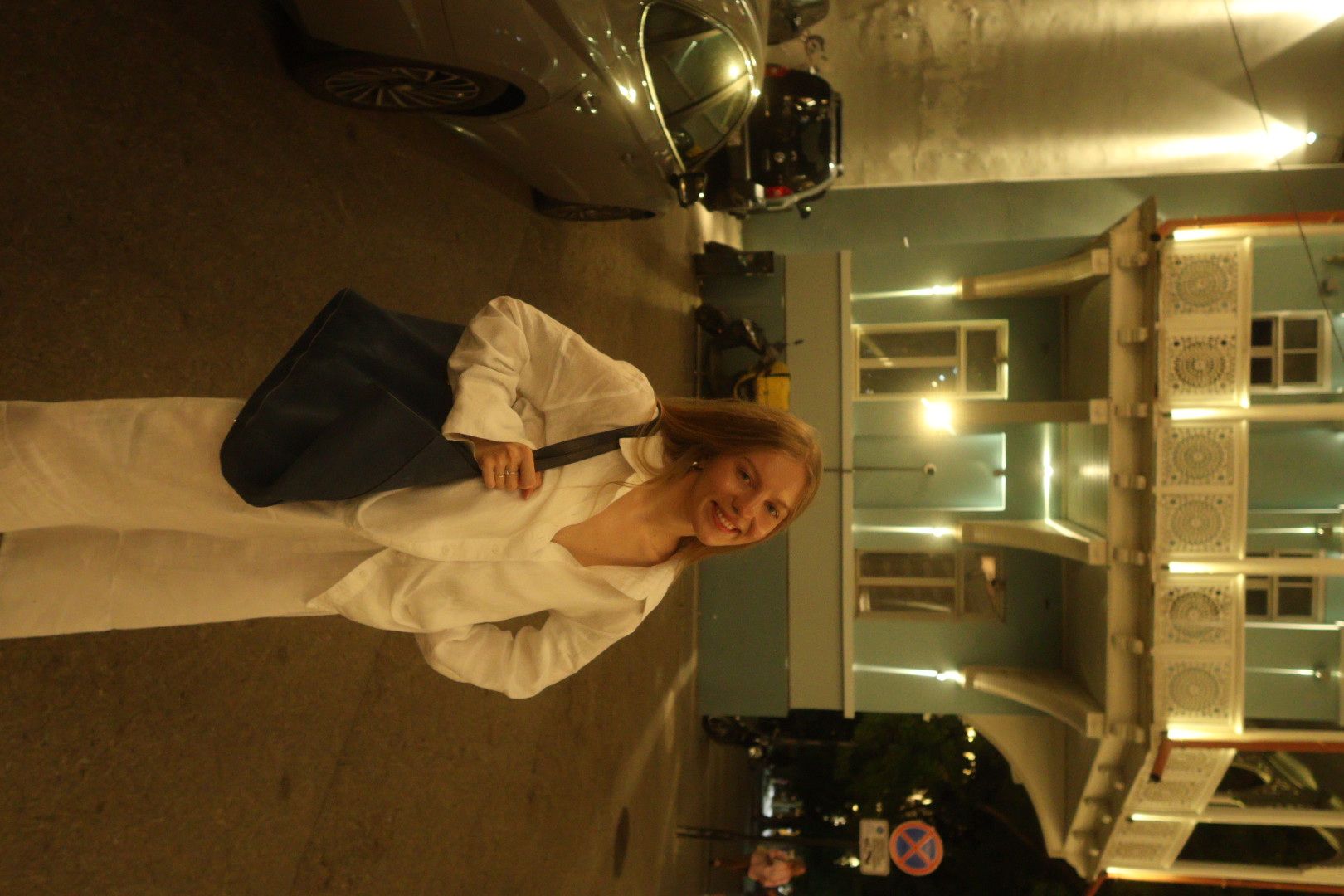 Vero smiling on a warmly lit city street at night